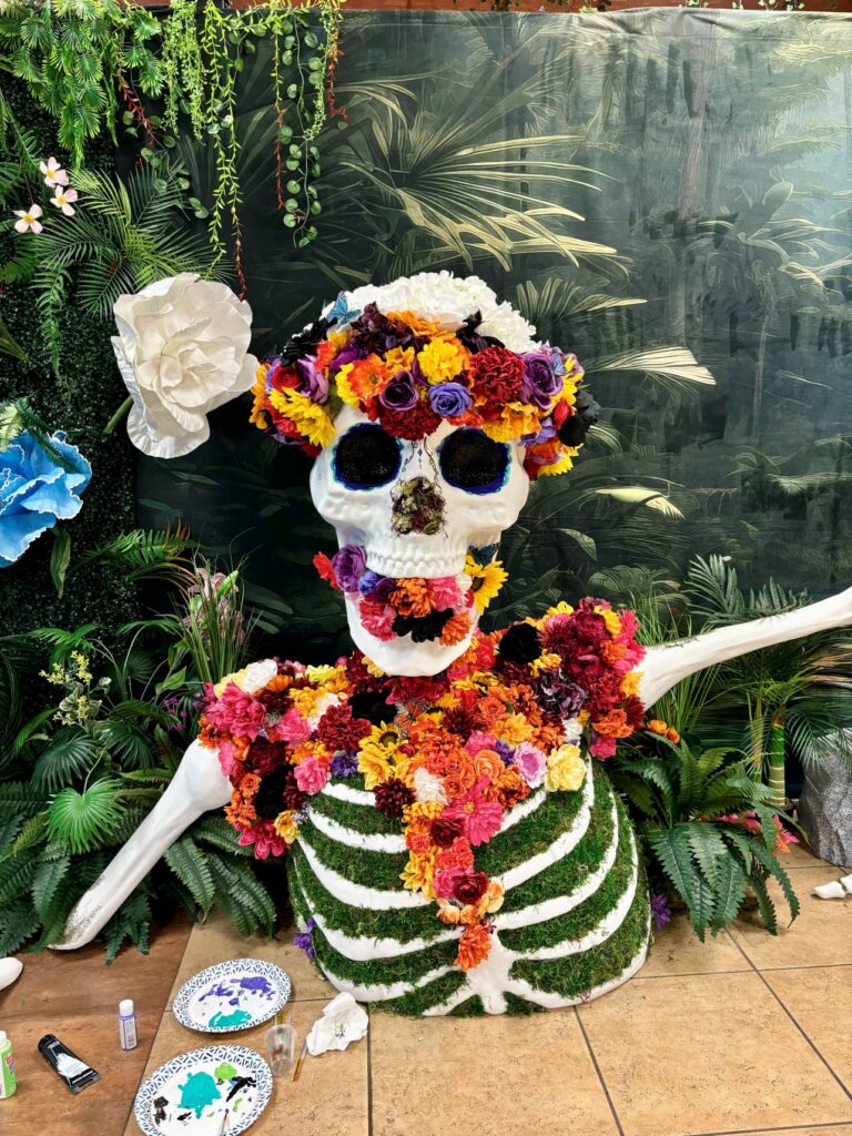 A skeleton being decorated for the Dia de los Muertos event sits on the floor