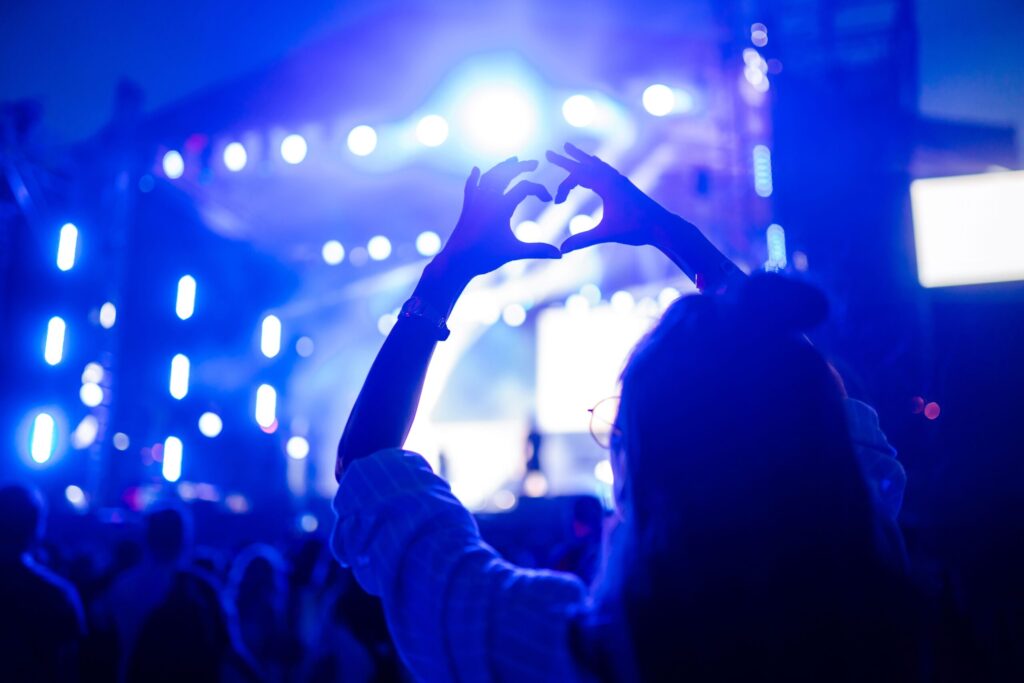 someone holding up heart hands at a concert