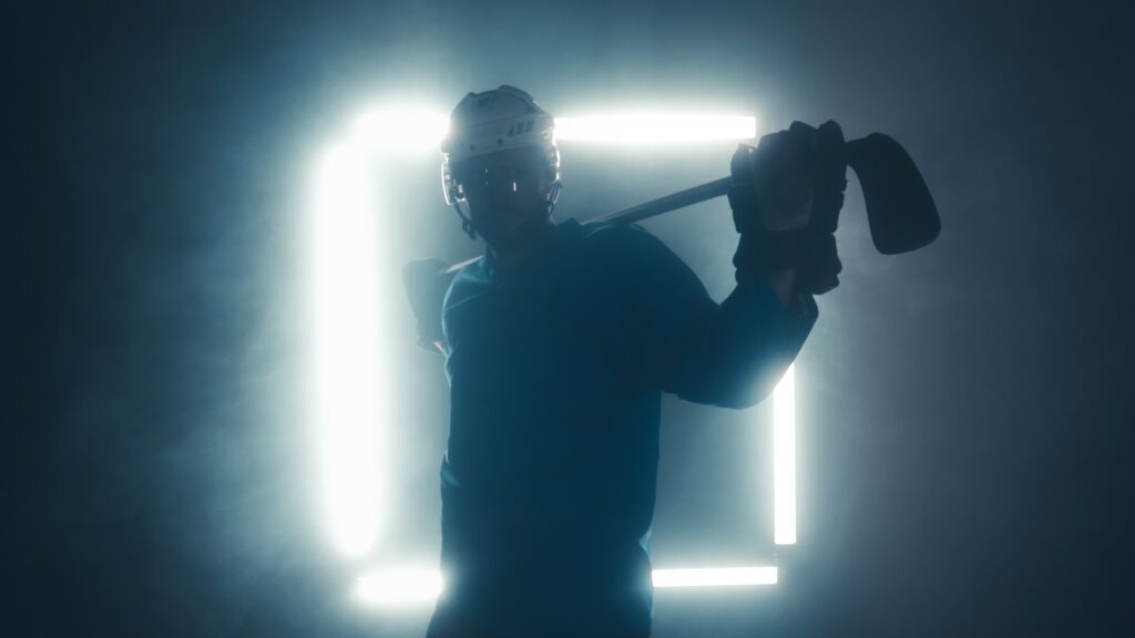 Portrait of male ice hockey player in uniform, looking into the camera, dramatic lighting