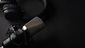 Studio black studio microphone with studio headphones on a black background.