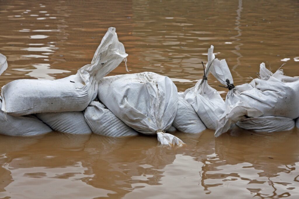 White sandbags for flood defense and brown water