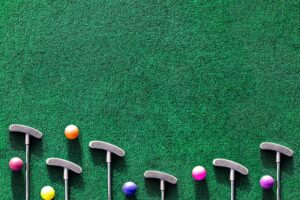 Multiple mini golf clubs and balls on putting green background
